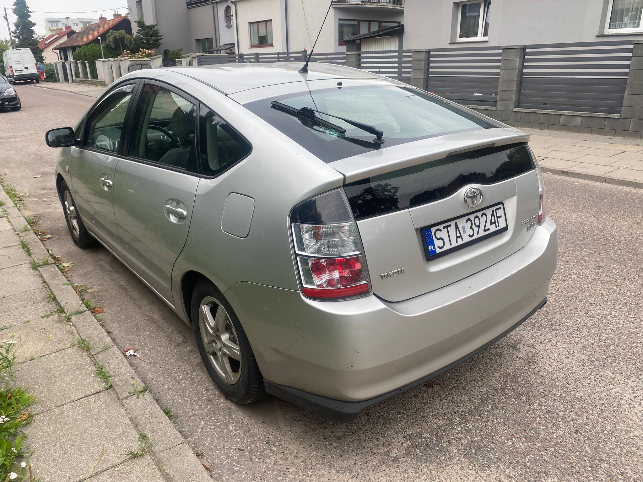 Srebrny samochód Toyota Prius zaparkowany na ulicy, widok z tyłu, tablica rejestracyjna STA 3924F.