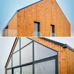 Dwupoziomowe ujęcie nowoczesnego budynku z drewnianą elewacją, dużymi przeszkleniami i czarnymi ramami okiennymi, widoczne balkony z szklanymi barierkami.