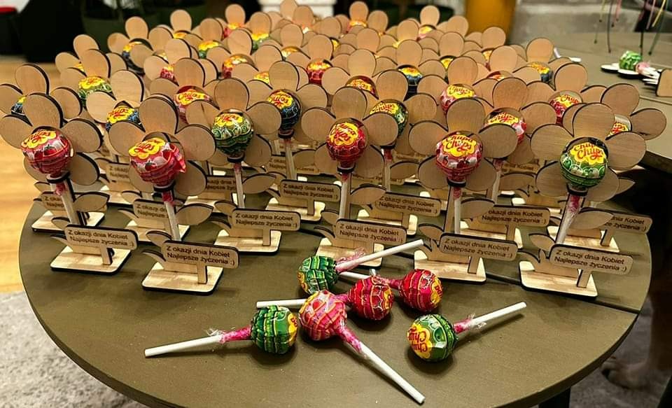 Duży bukiet lizaków Chupa Chups w kształcie kwiatów z drewnianymi płatkami i podstawkami z napisem 'Z okazji Dnia Kobiet. Najlepsze życzenia'.