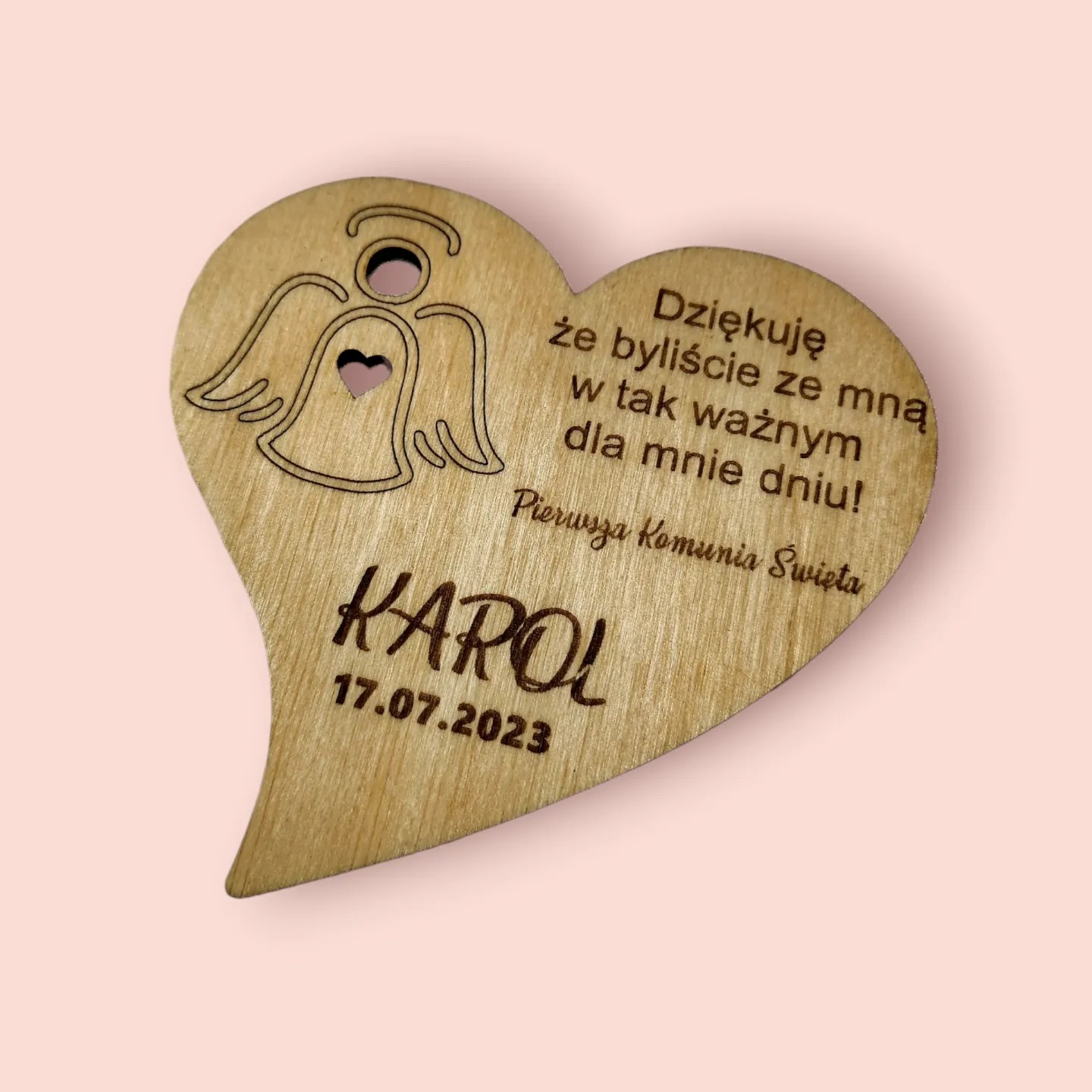 Drewniane serce z grawerowanym napisem 'Dziękuję, że byliście ze mną w tak ważnym dla mnie dniu! Pierwsza Komunia Święta', imieniem 'Karol' i datą 17.07.2023, ozdobione wyciętym wzorem anioła...