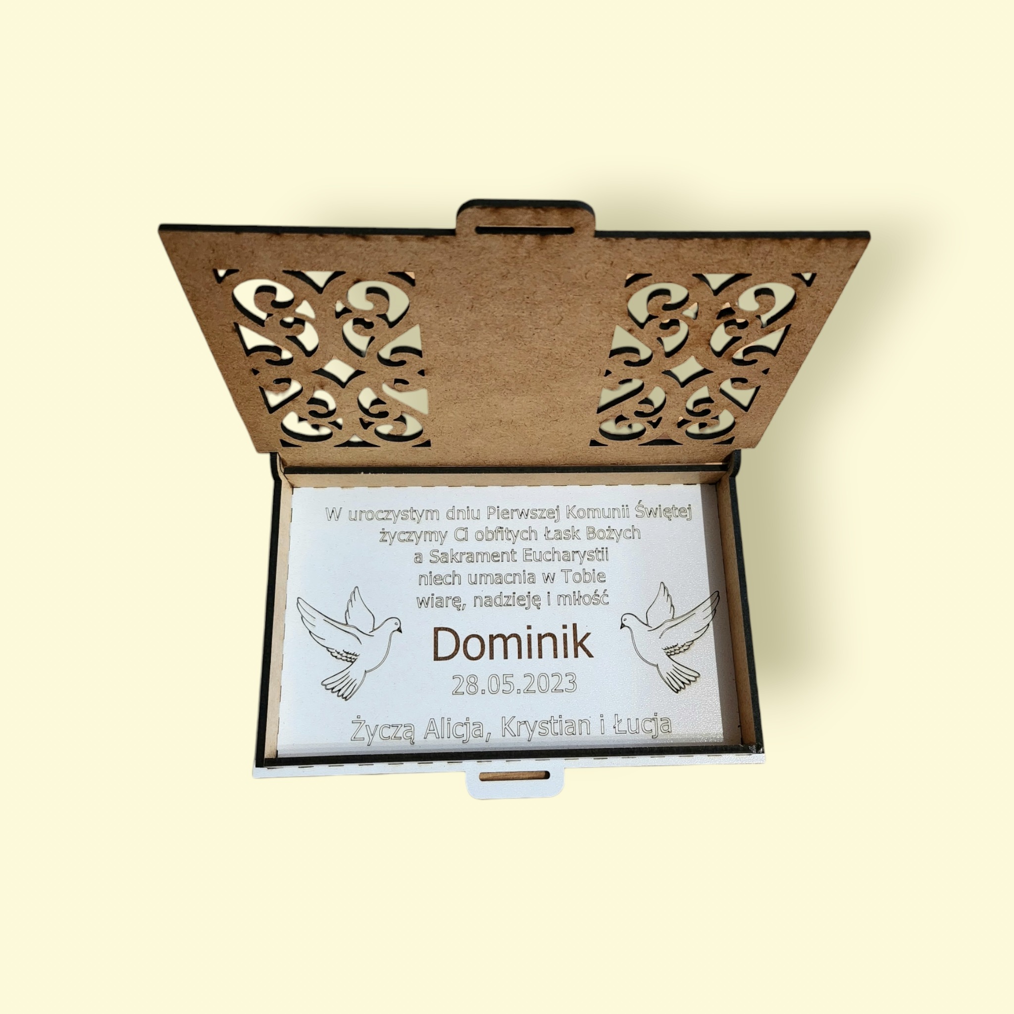 Otwarty, drewniany, ażurowy kosz prezentowy z wygrawerowaną dedykacją na Pierwszą Komunię Świętą dla Dominika, z datą 28.05.2023 i życzeniami od Alicji, Krystiana i Łucji.