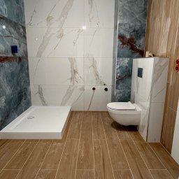 BurbanBud - Nowoczesna łazienka po remoncie: kabina prysznicowa, podwieszana toaleta, marmurowe i drewnopodobne płytki. Całość w jasnych barwach.