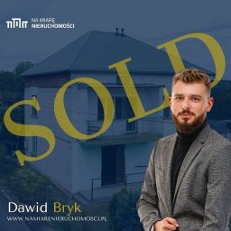 Na Miarę Nieruchomości - Mężczyzna w marynarce na tle domu z napisem SOLD, prezentacja oferty nieruchomości.