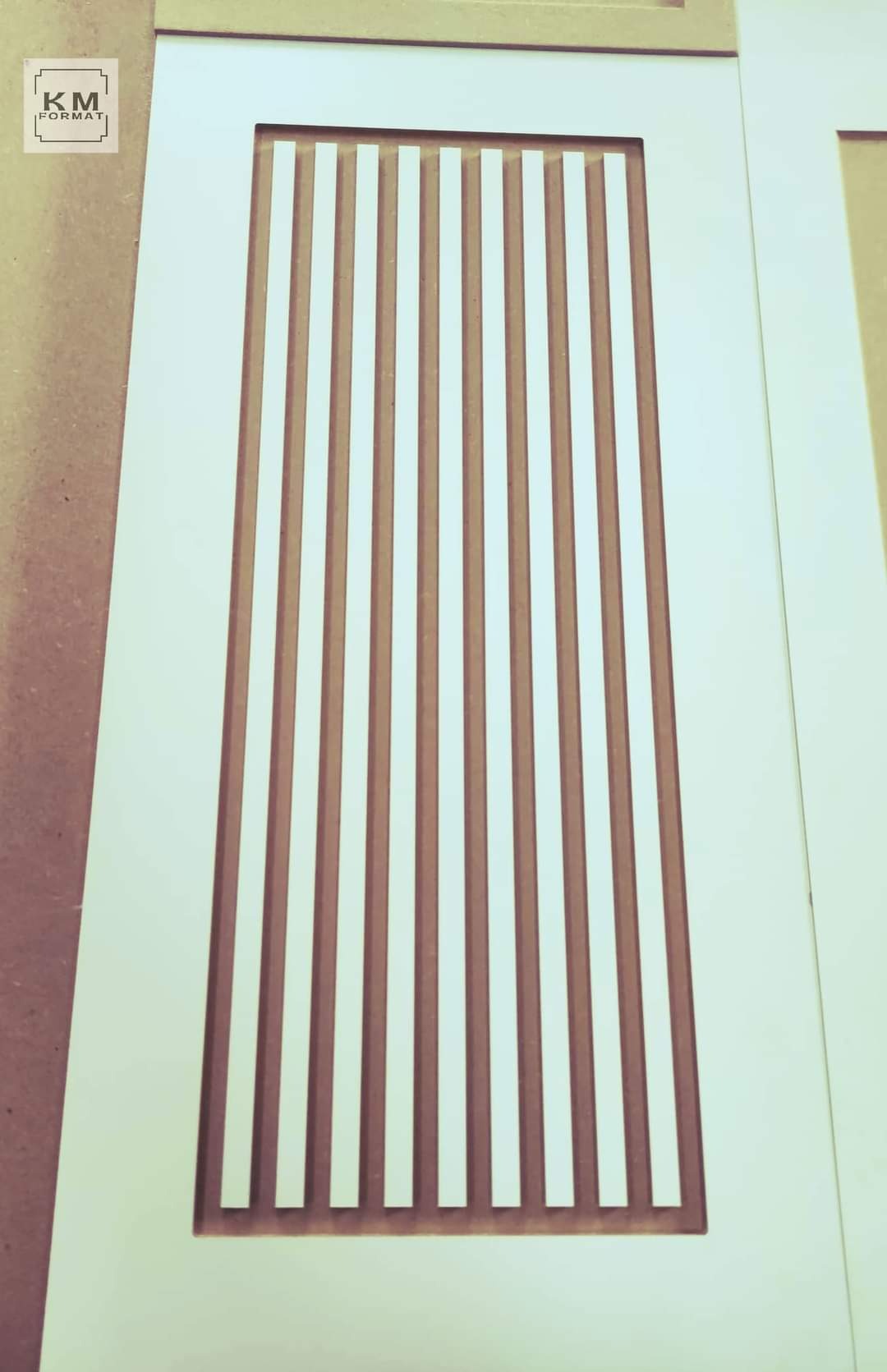 Białe drzwi drewniane z pionowymi, brązowymi listwami, widoczne logo firmy w lewym górnym rogu.