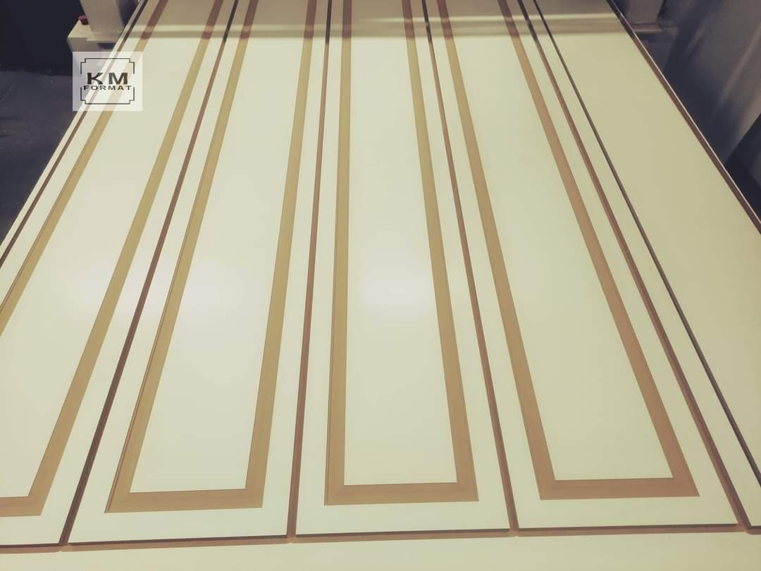 Białe fronty meblowe z dekoracyjnymi, drewnianymi ramkami w odcieniach beżu, ułożone obok siebie, widoczne z perspektywy.