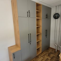 Gggg - Szara szafa wnękowa z drewnianymi akcentami i otwartymi półkami, zamek w drzwiach, widok na parkiet i rury grzewcze.