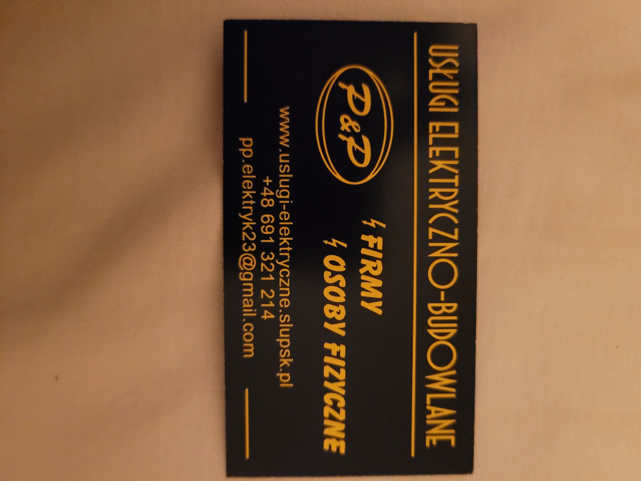 Wizytówka firmy P&P oferującej usługi elektryczno-budowlane, z logo, adresem strony internetowej, numerem telefonu i adresem e-mail.