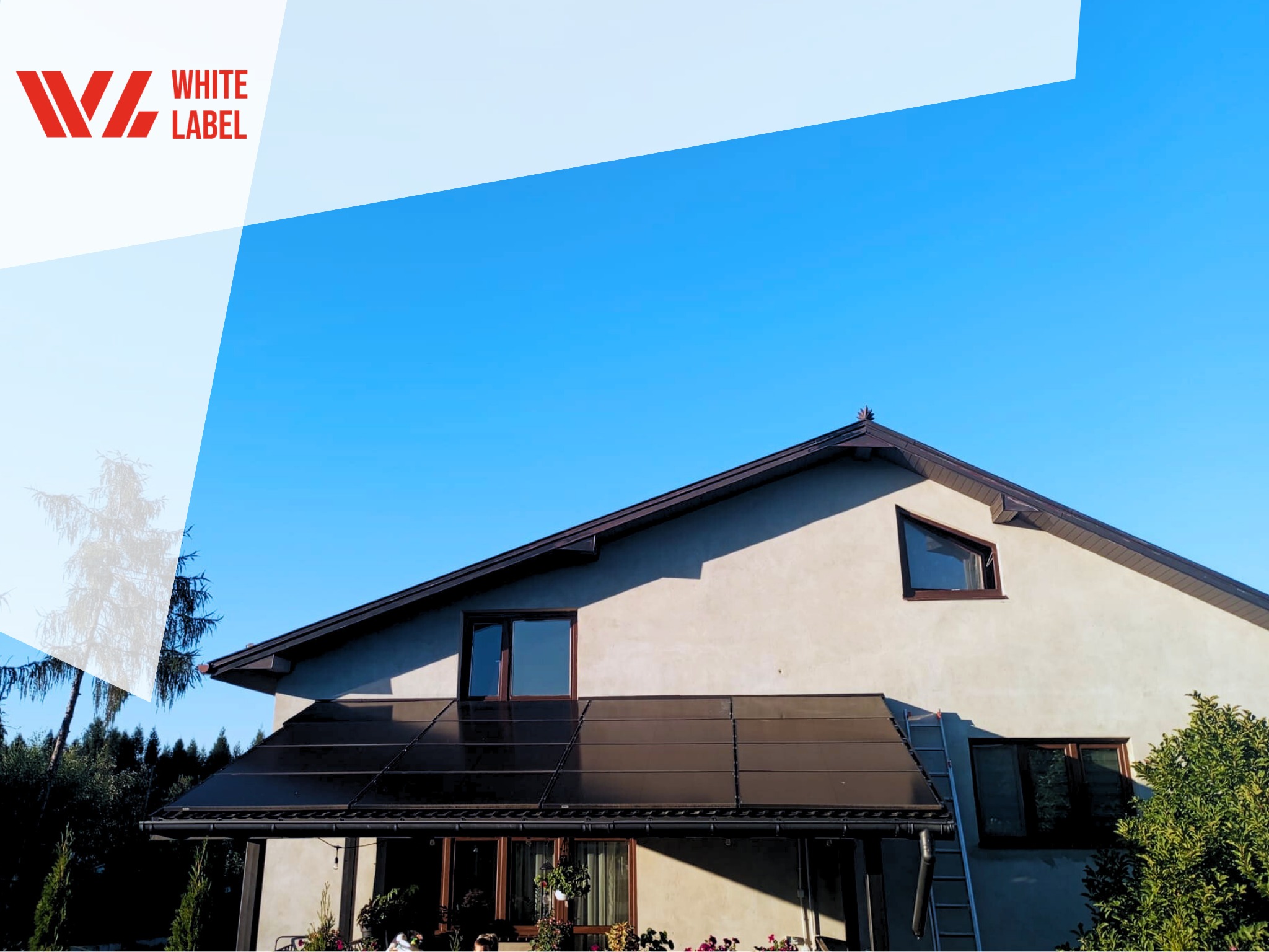 Dom jednorodzinny z panelami fotowoltaicznymi zamontowanymi nad werandą, błękitne niebo w tle, widoczne logo firmy w lewym górnym rogu.