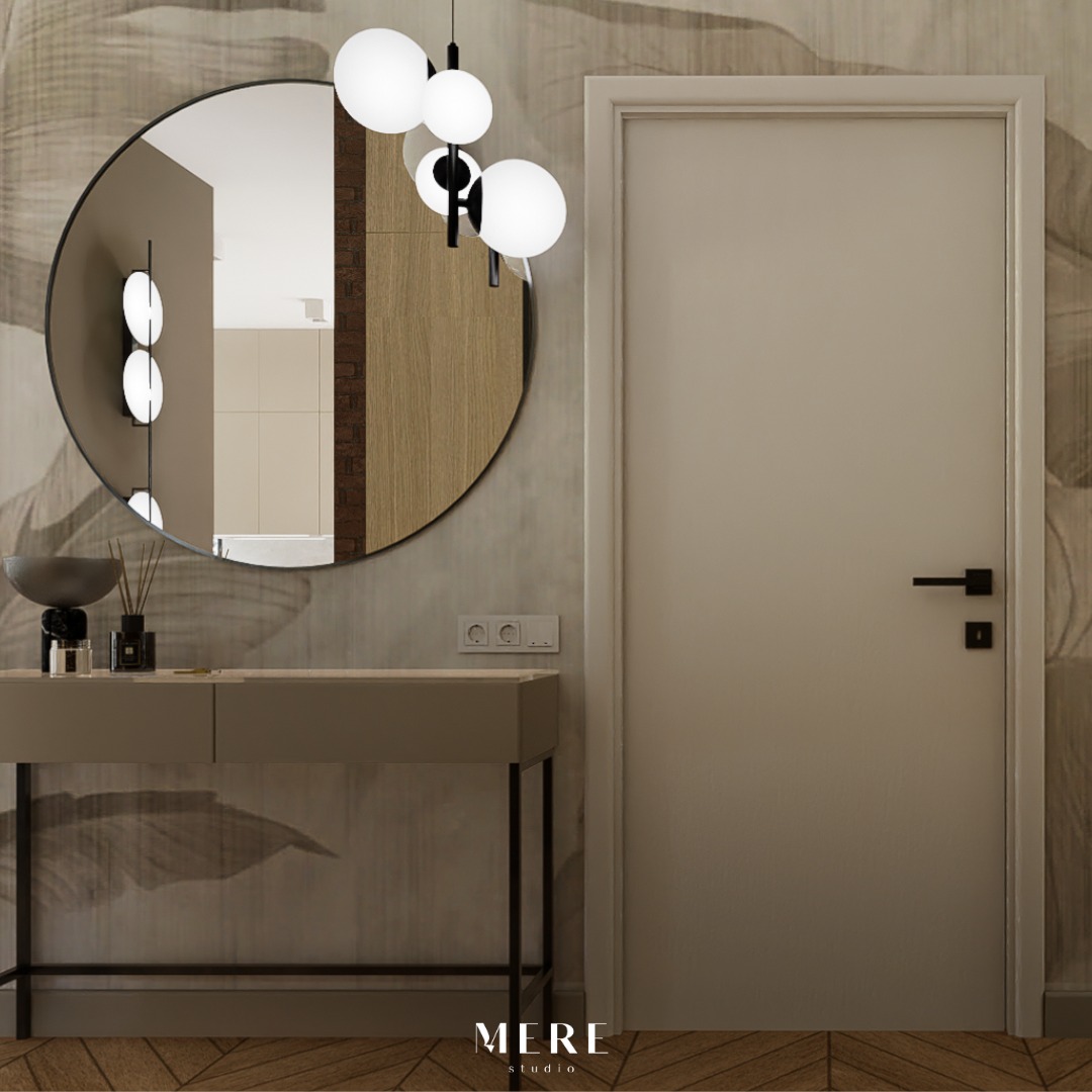 Wnętrze przedpokoju z okrągłym lustrem, konsolą i nowoczesną lampą wiszącą z kulistymi kloszami na tle ściany z motywem roślinnym i zamkniętych drzwi.