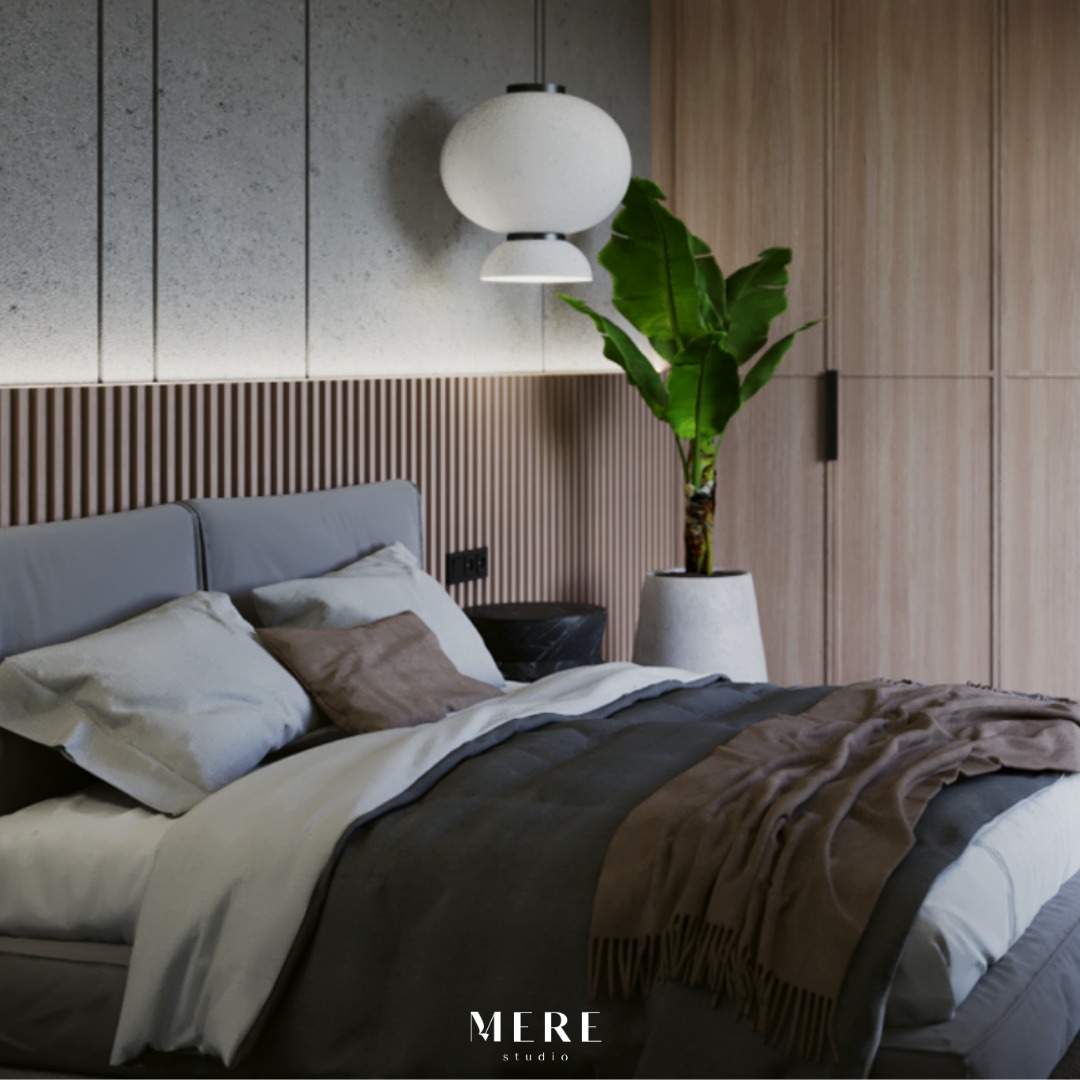 Nowoczesna sypialnia z szarą tapicerką łóżka, drewnianą ścianą z lameli, okrągłą lampą wiszącą i dużą rośliną doniczkową.