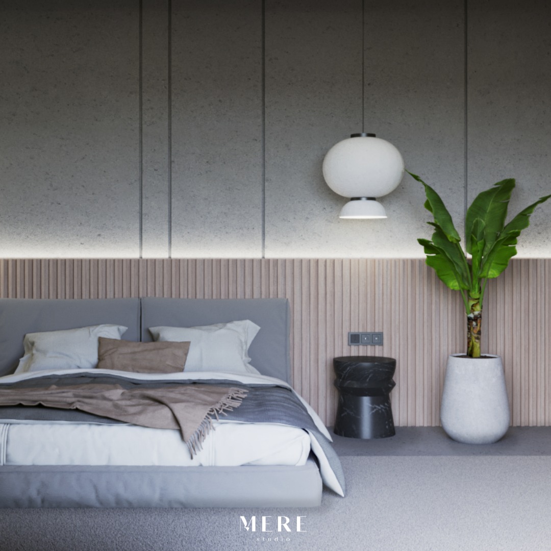 Minimalistyczna sypialnia z szarym łóżkiem, drewnianym panelem ściennym, kulistą lampą i rośliną w białej donicy, uzupełniona czarnym stolikiem nocnym.