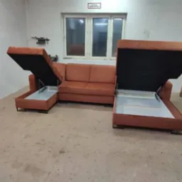 Brązowa sofa narożna z podnoszonymi siedziskami, ukazującymi schowki, sfotografowana w warsztacie.