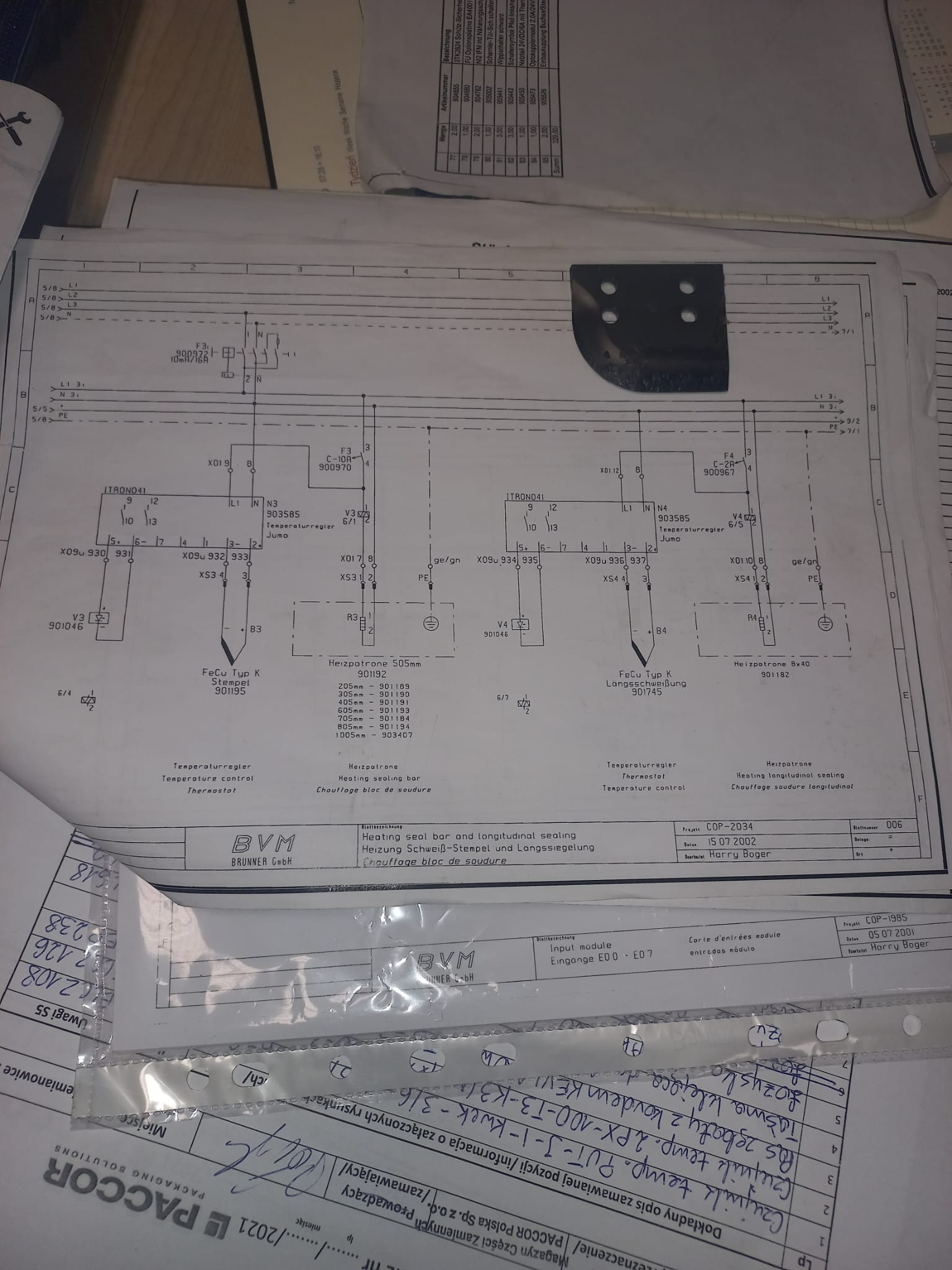 Schemat elektryczny z odręcznymi notatkami, częściowo zakryty innymi dokumentami, widoczne oznaczenia elementów i parametry techniczne.