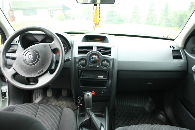 Wnętrze Renault Megane II z widoczną deską rozdzielczą, kierownicą z logo Renault oraz zawieszką zapachową na lusterku.