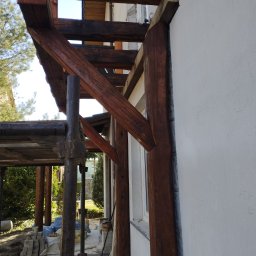 Balkon drewniany ze starego modrzewia z rzeźbionymi słupami oraz mieczami.