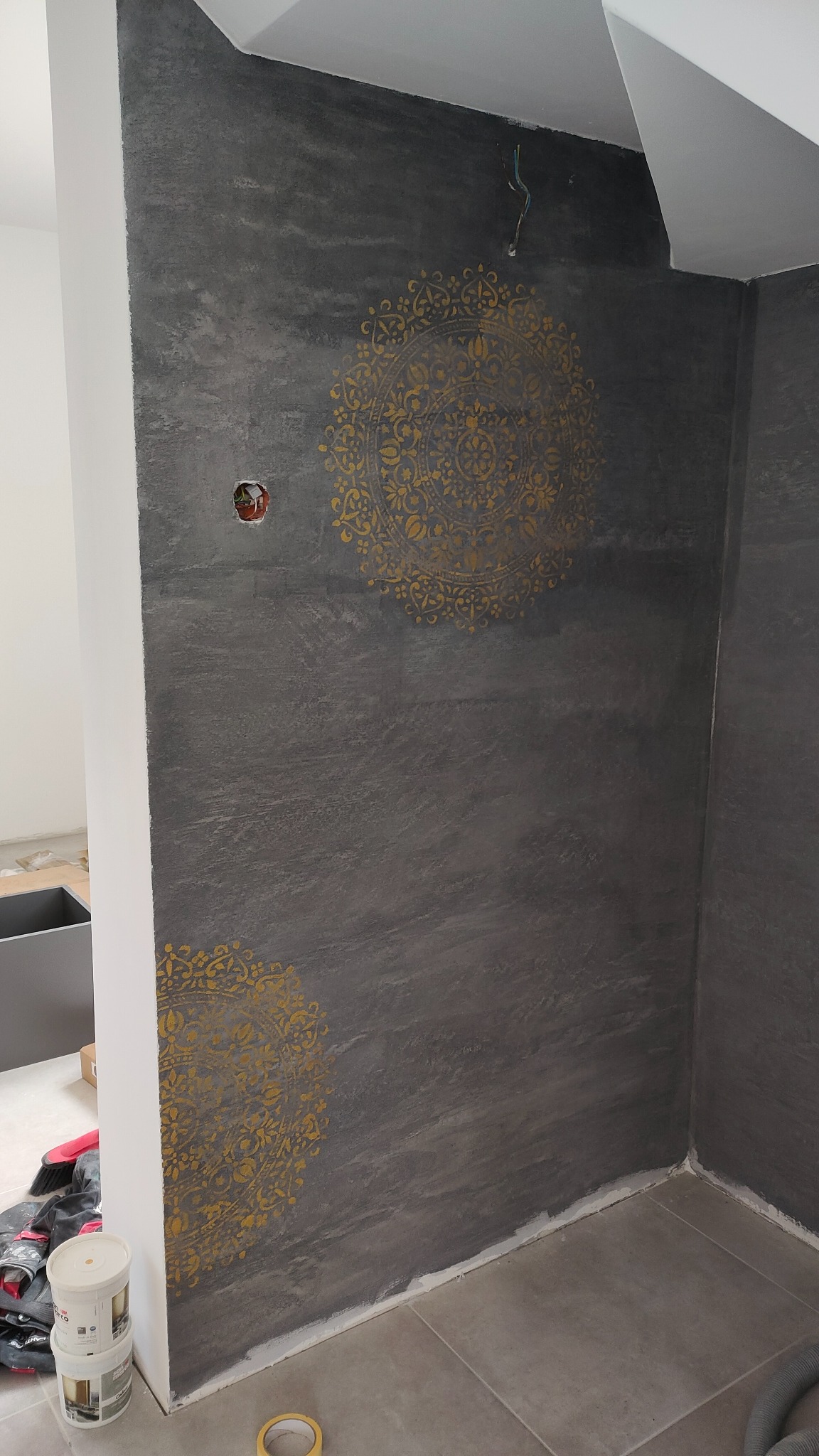 trawertyn pod klatką schodową z złotymi mandalami