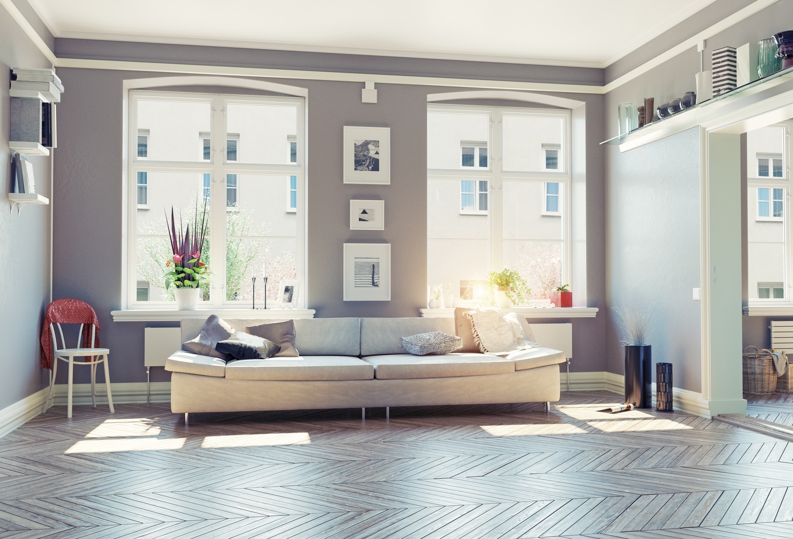 Jasny salon z szarą ścianą, dwoma dużymi oknami w białych ramach, beżową sofą z poduszkami, parkietem w jodełkę, dekoracjami okiennymi i minimalistycznymi obrazkami na ścianie.