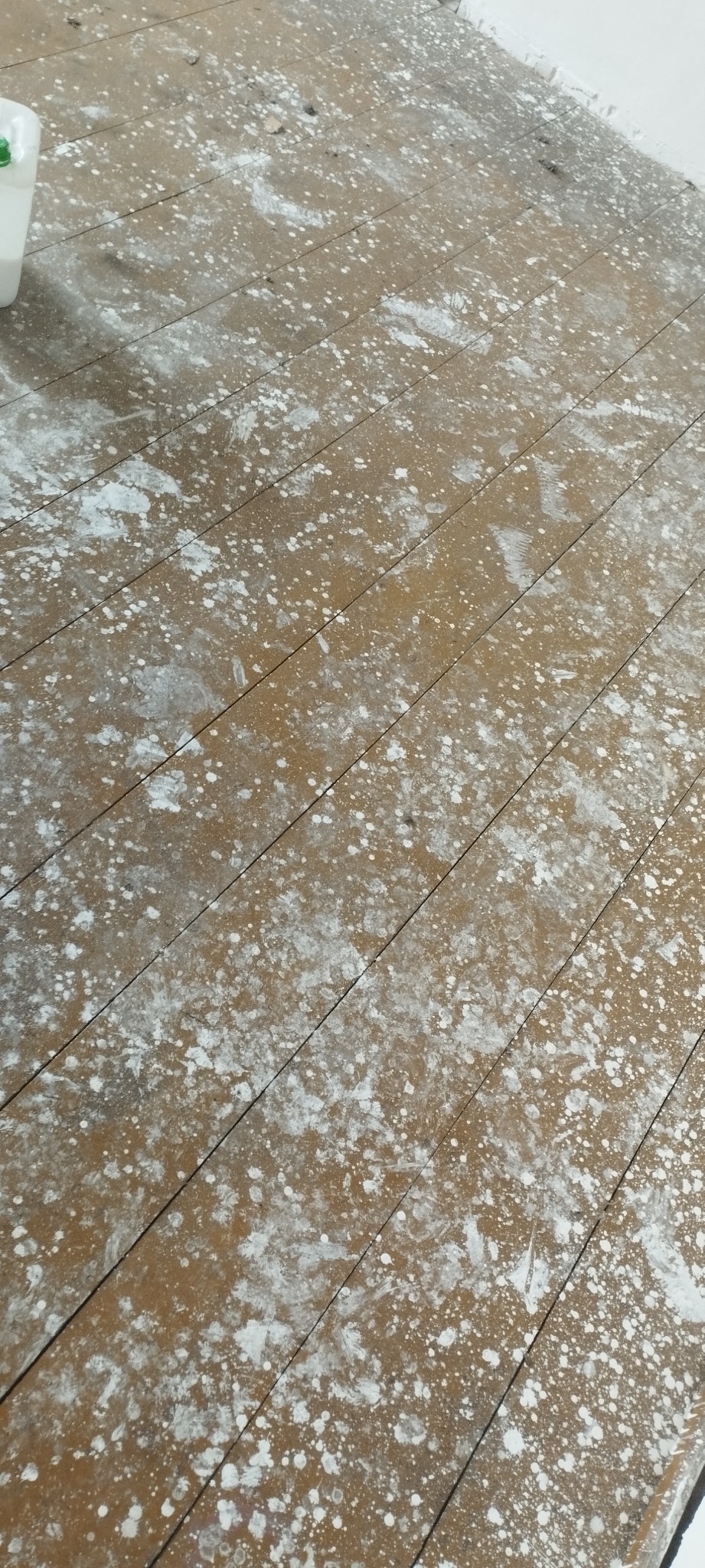 Drewniana podłoga z widocznymi plamami i zabrudzeniami po remoncie w Radomsku, wymagająca sprzątania.