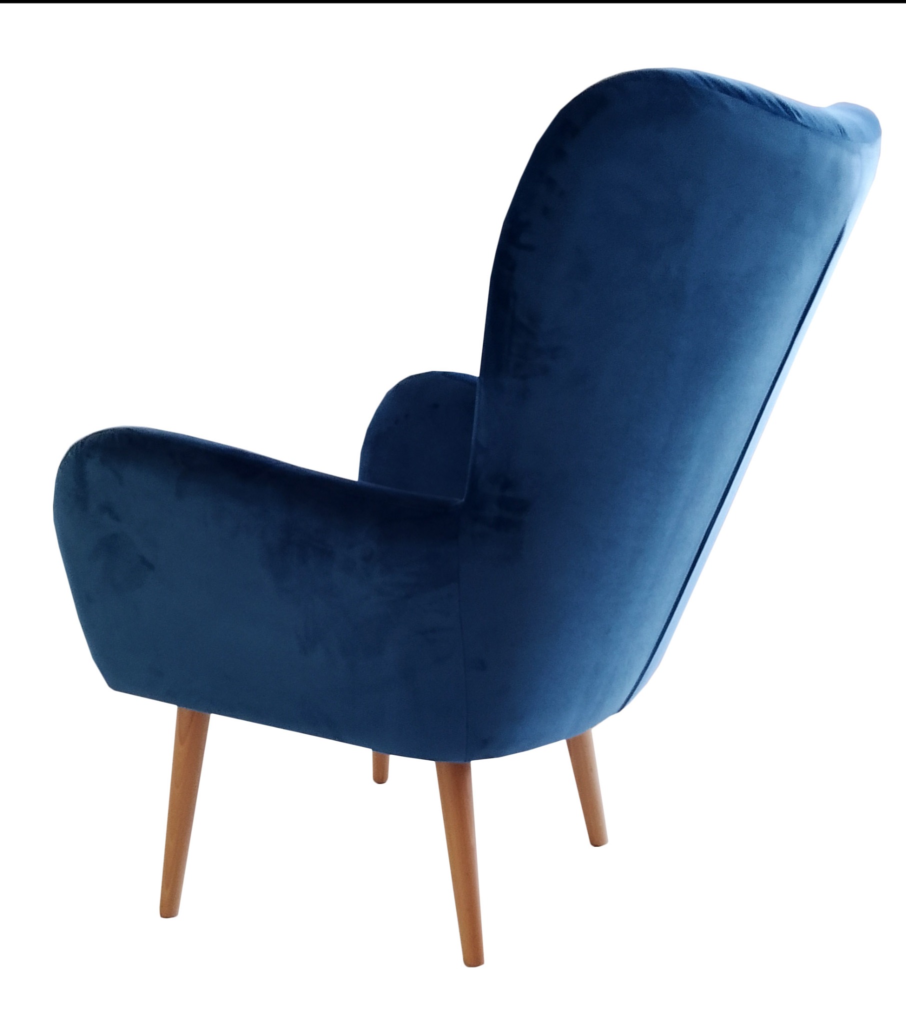 Tył fotela klubowego obitego niebieskim welurem, stojącego na czterech drewnianych nóżkach, na białym tle.