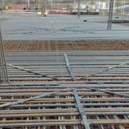 Siatka zbrojeniowa na budowie w Rajczy, przygotowana do zalania betonem, widoczne pionowe pręty i poziome wiązania.