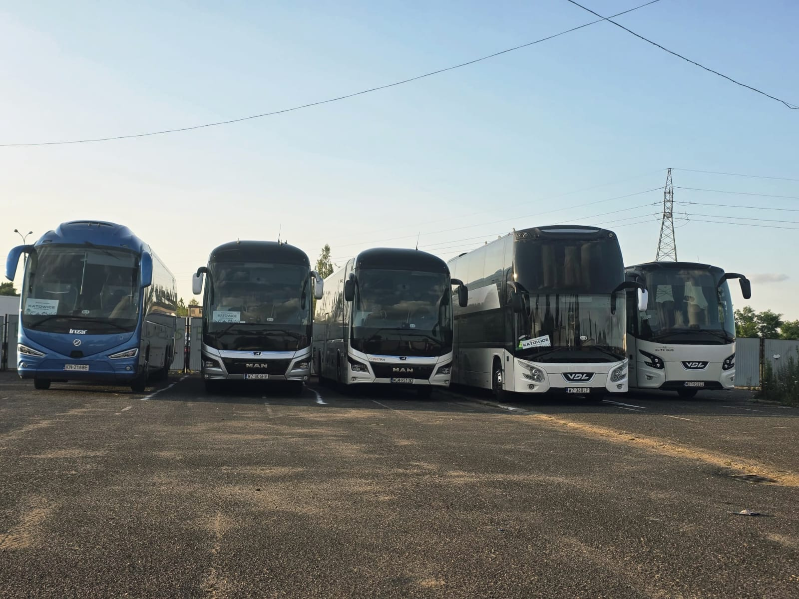 Flota autobusów różnych marek (Irizar, MAN, VDL) zaparkowana na placu, z widocznymi tablicami rejestracyjnymi i oznaczeniami 'Katowice'.