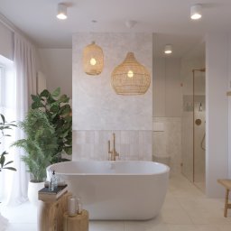 Kreślarnia studio projektowania wnętrz - Jasna łazienka w stylu boho z wolnostojącą wanną, złotą armaturą, plecionymi lampami i roślinami doniczkowymi, oświetlona światłem dziennym.