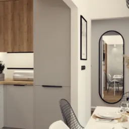 Nowoczesna kuchnia z drewnianymi i szarymi szafkami, czarnym piekarnikiem, drewnianym blatem, roślinami w doniczkach i widokiem na jadalnię z lustrem.