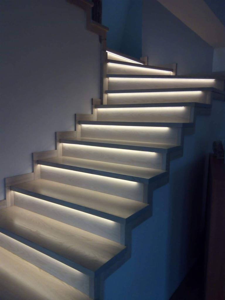 Drewniane schody z podświetleniem LED na każdym stopniu, wykonane w Sierakowicach, oświetlające klatkę schodową.