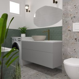 Weronika Więczkowska - Wizualizacja nowoczesnej łazienki z umywalką nablatową, złotą baterią, wiszącą toaletą i pralką schowaną za blatem, z zielonymi płytkami i terazzo oraz roślinami doniczkowymi.
