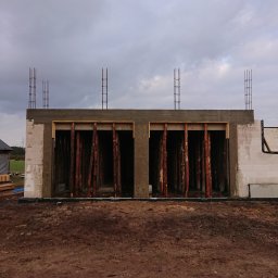 Daniel Gut USŁUGI OGÓLNOBUDOWLANE - Wznoszenie ścian budynku z betonu komórkowego, widoczne drewniane stemple podtrzymujące nadproże i wystające pręty zbrojeniowe
