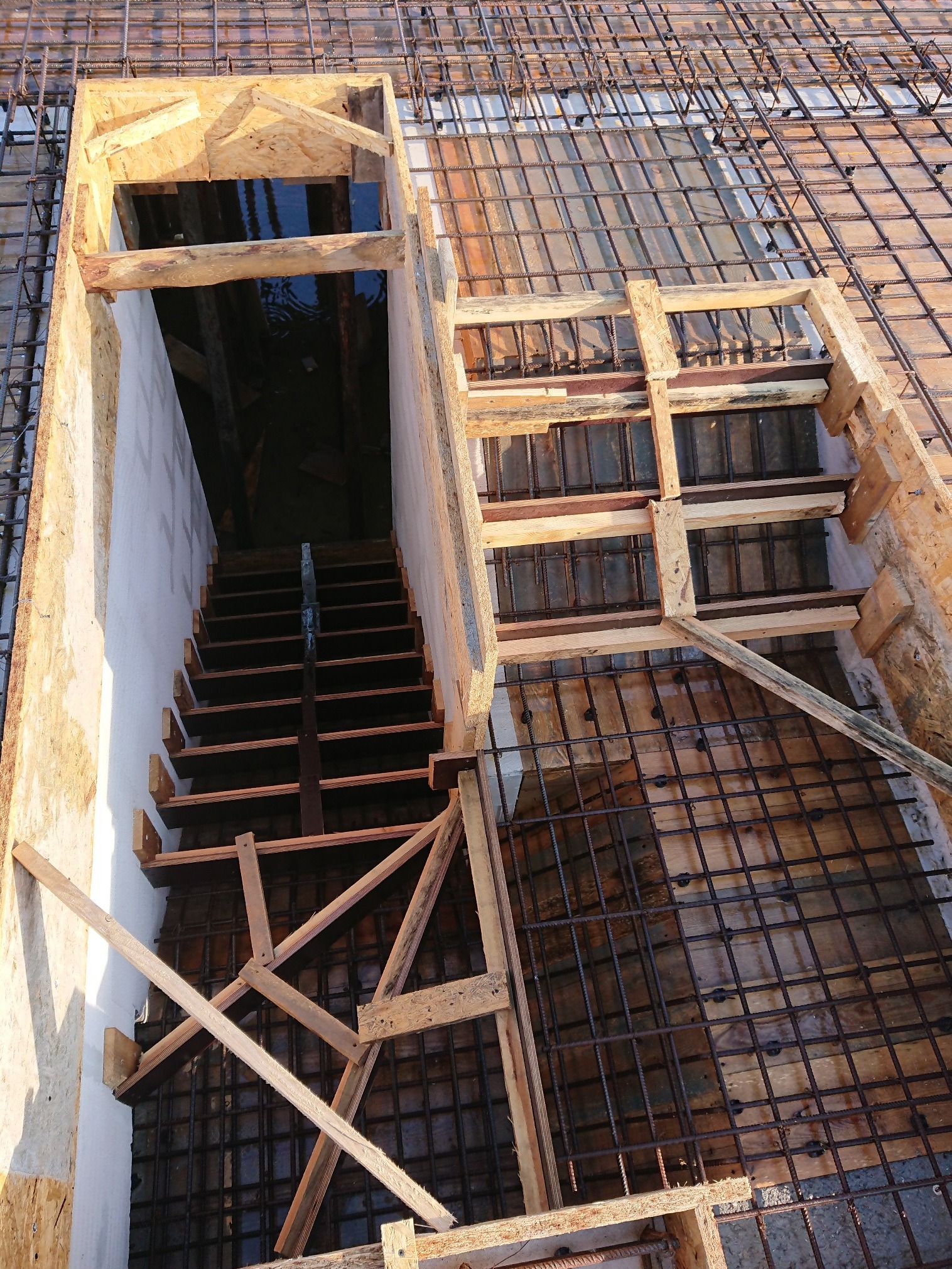 Zbrojenie fundamentów z deskowaniem schodów w trakcie budowy, widok z góry.