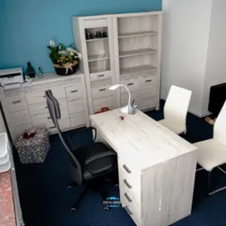 Jasne biuro z biurkiem, krzesłami, szafką i kwiatami w tle, widok z góry.