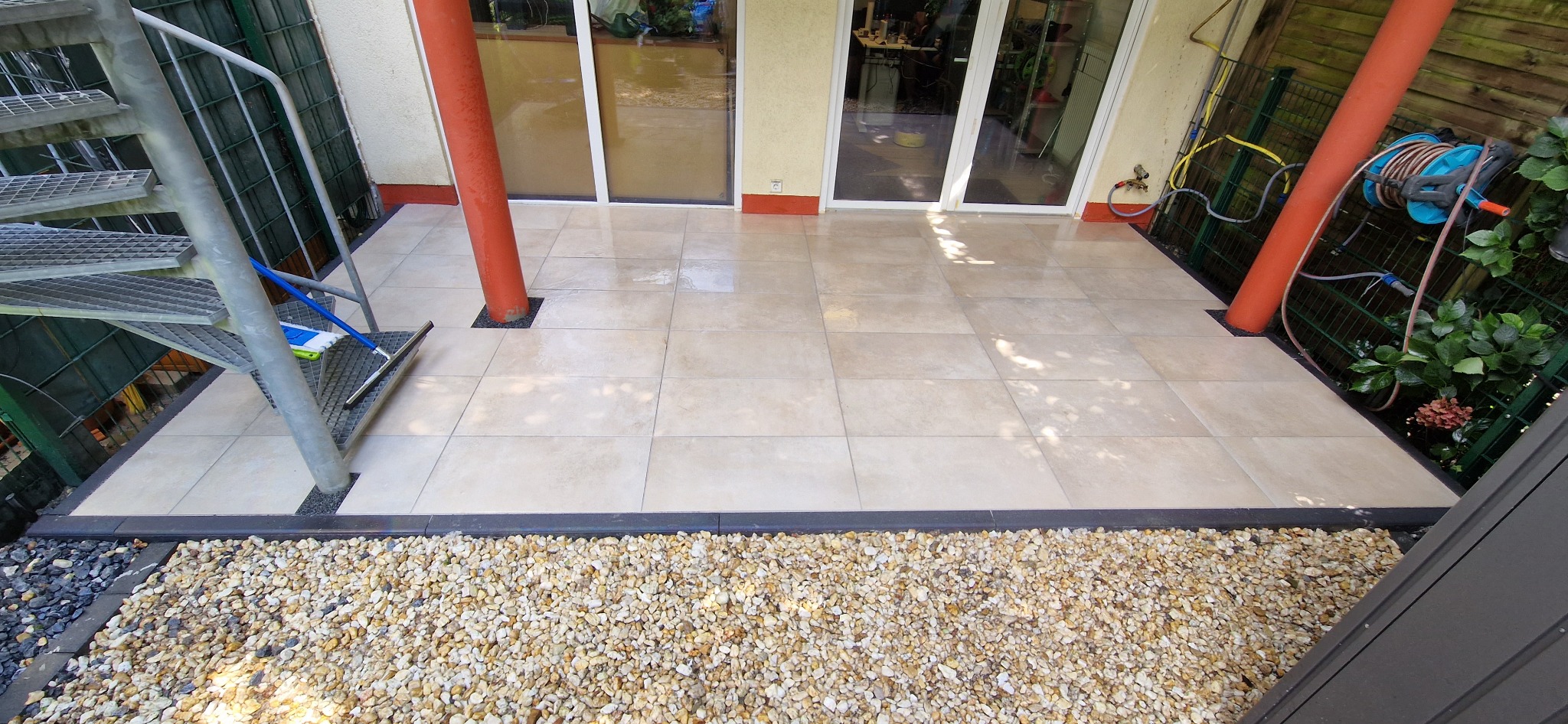 Jasne płytki podłogowe na zewnątrz, otoczone drobnym żwirem i schodami spiralnymi z boku