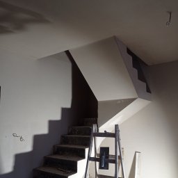 PRO100TYNKI - Świeżo położone gładzie gipsowe na klatce schodowej w Robakowie. Widoczne narzędzia i drabina malarska. Jasne, jednolite ściany.