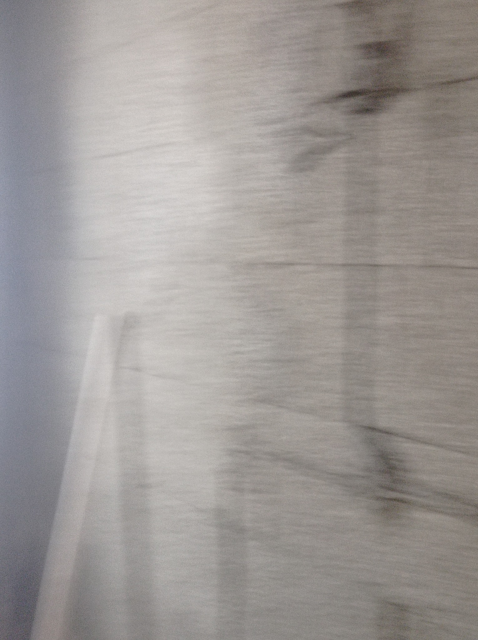 Niedokładne ujęcie szarej ściany z widoczną strukturą imitującą drewno, prawdopodobnie po nałożeniu tynku strukturalnego.