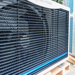 MS Power Sp. z o.o. - Dwie jednostki zewnętrzne klimatyzacji lub wentylacji, ustawione na drewnianych paletach, z widocznymi żaluzjami i wentylatorami, oświetlone naturalnym światłem.
