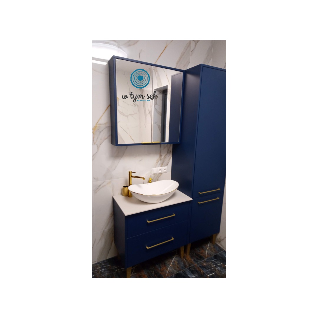 Granatowa zabudowa łazienkowa z umywalką nablatową i lustrem z logotypem w Rawa Mazowiecka, złote detale, marmurowe płytki w tle.