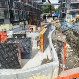 Budowa fundamentów pod budynek z użyciem szalunków PERI, widoczny dźwig budowlany w tle, teren budowy z rusztowaniami.