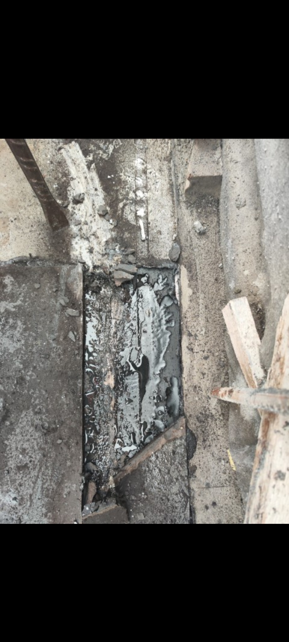 Fragment starego, uszkodzonego dachu z widocznymi śladami smoły i uszczelnieniami, ukazujący proces naprawy lub wymiany pokrycia dachowego.