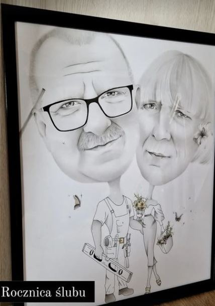 Oprawiony w ramę czarno-biały portret karykaturalny pary: mężczyzna w okularach z wąsami trzyma poziomicę i ma na sobie kombinezon roboczy, a kobieta trzyma bukiet kwiatów i ma kwiat we włosach...
