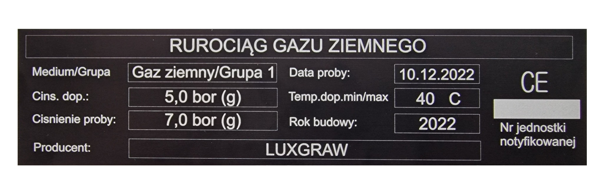 Tabliczka znamionowa rurociągu gazu ziemnego z informacjami technicznymi, datą próby, ciśnieniem, temperaturą i rokiem budowy, wykonana przez producenta LUXGRAW.