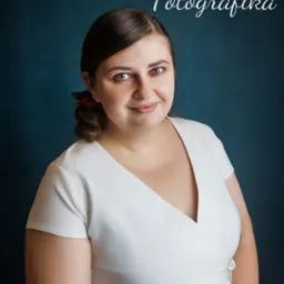 Portret uśmiechniętej kobiety w białej sukience na ciemnym tle, z logo firmy fotograficznej w górnej części kadru.