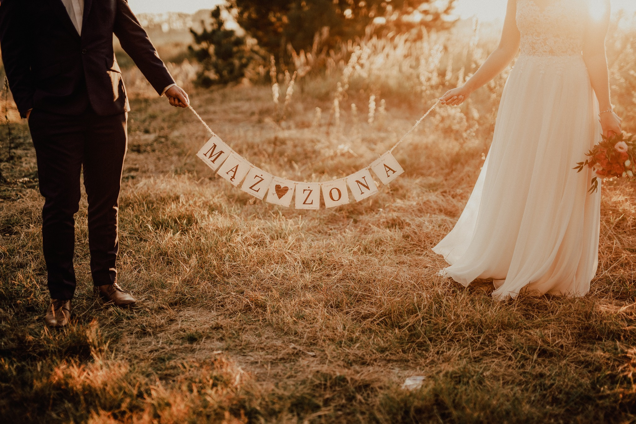 Para młoda trzymająca transparent z napisem 'Mąż i Żona' w jesiennej scenerii podczas sesji zdjęciowej w plenerze.