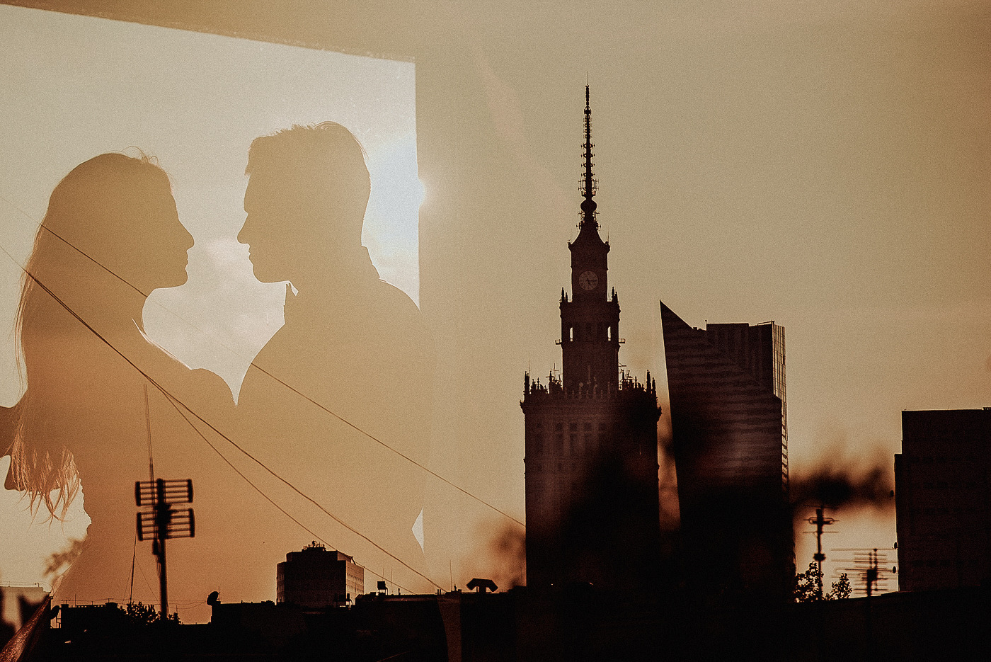 Sylwetki pary na tle Pałacu Kultury i Nauki w Warszawie, z efektem podwójnej ekspozycji i ciepłą tonacją.
