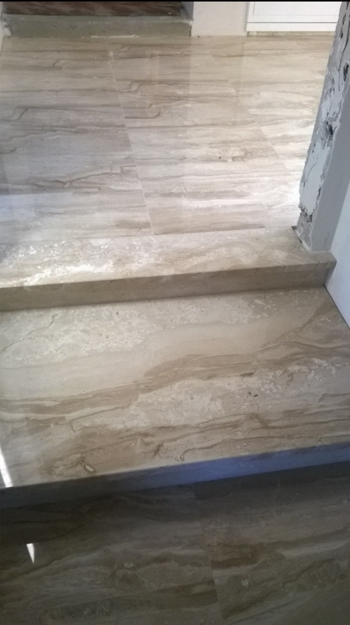 Schody wyłożone płytkami imitującymi marmur w odcieniach beżu i brązu, widoczne w Borne Sulinowo, z detalami wykończenia przy ścianie.