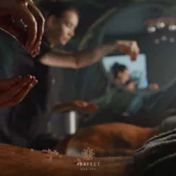 Nakładanie drobnych kryształków na skórę podczas zabiegu, widoczne dłonie terapeuty i odbicie w lustrze, logo spa w dolnej części kadru.