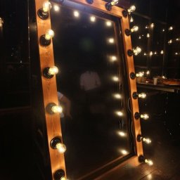 MEMBOX SPÓŁKA Z OGRANICZONĄ ODPOWIEDZIALNOŚCIĄ - Drewniana fotobudka z lustrem i żarówkami w stylu retro, widoczne odbicia osób i elementy wystroju wnętrza.