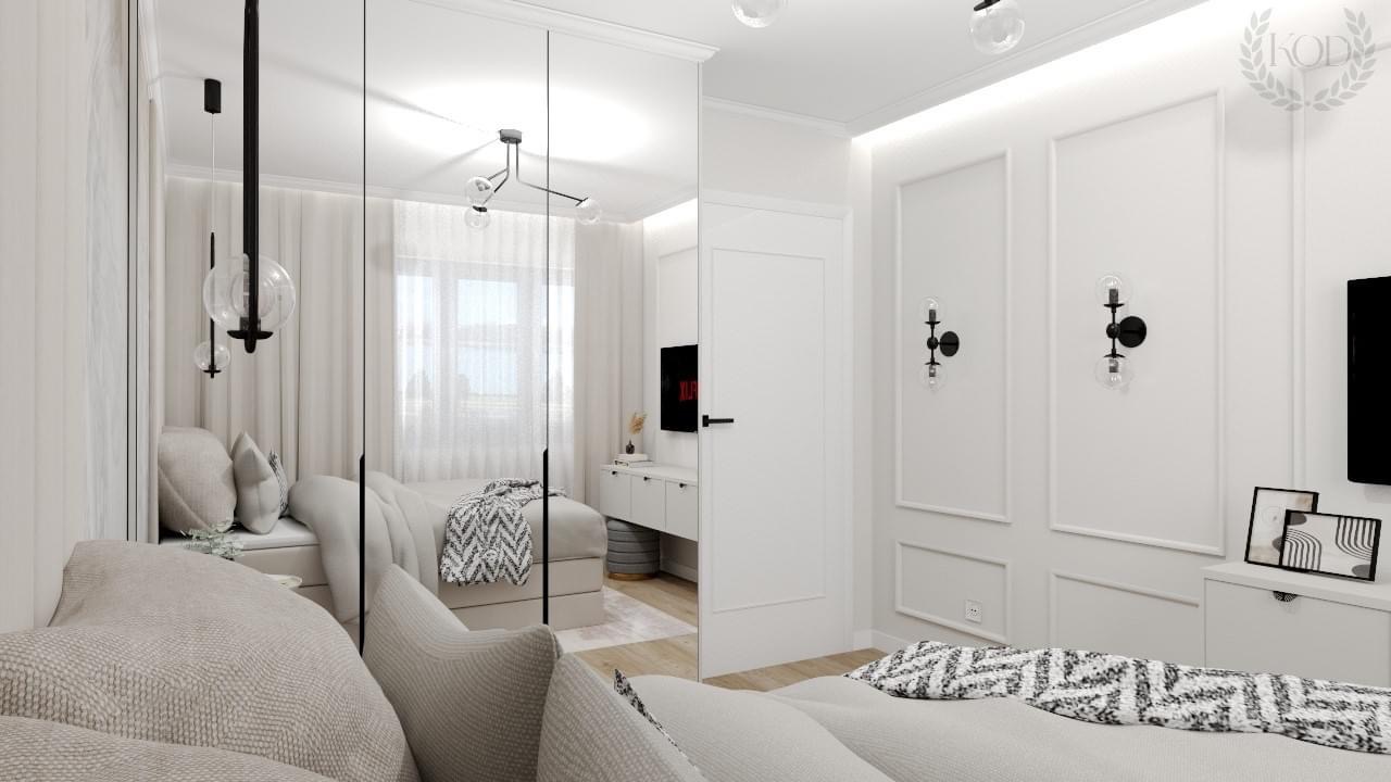 Nowoczesna aranżacja sypialni z lustrzanymi drzwiami szafy, szarą sofą, dekoracyjnymi lampami ściennymi i subtelnym oświetleniem sufitowym, widoczne odbicie łóżka z wzorzystą narzutą.