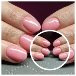 Dłonie z delikatnym, różowym manicure hybrydowym o drobinkowym wykończeniu, prezentowane w okrągłej ramce, ukazujące zbliżenie na stylizację paznokci.