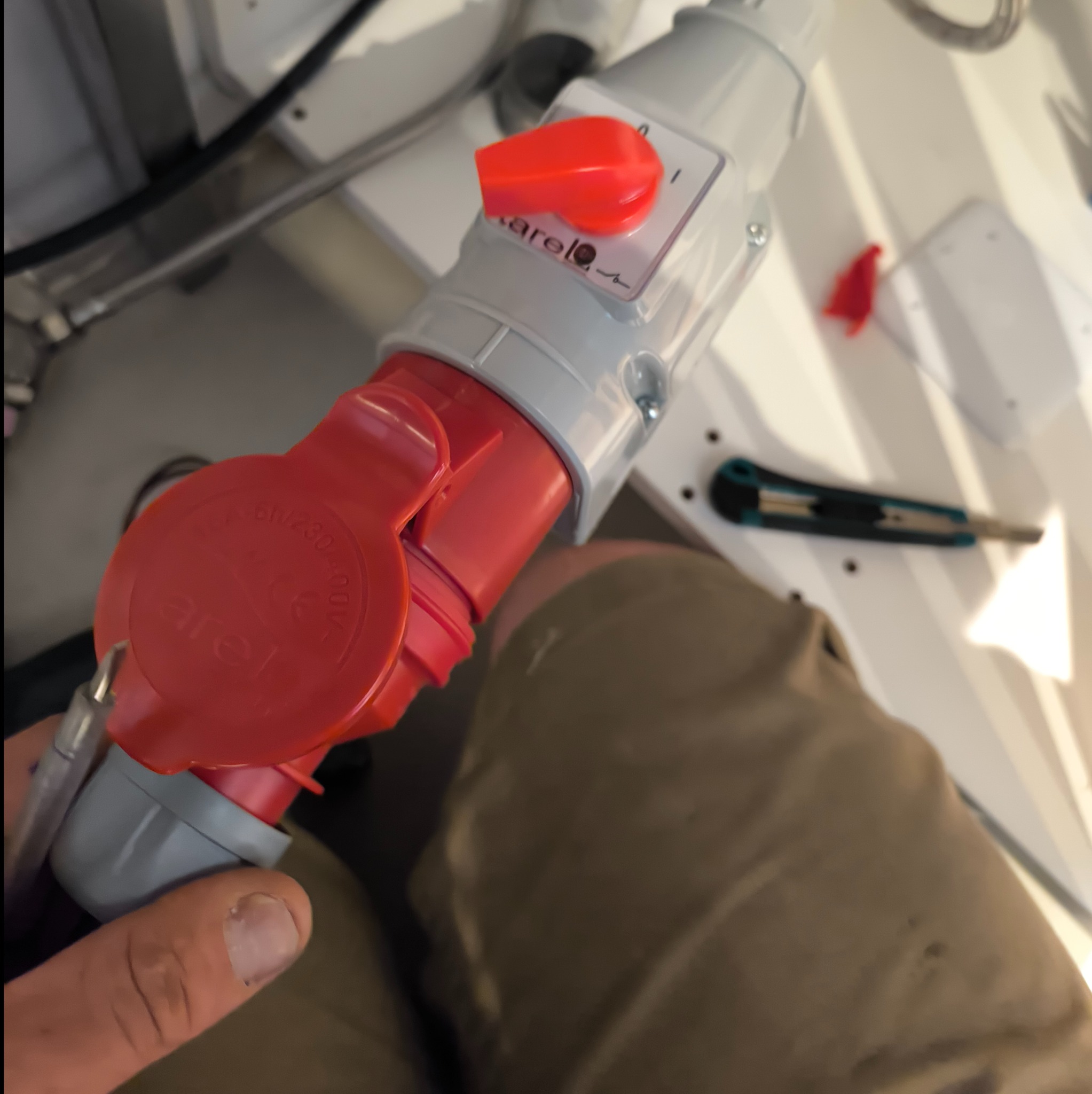 Podłączenie przemysłowej wtyczki elektrycznej Arelo, widoczny nóż monterski w tle.